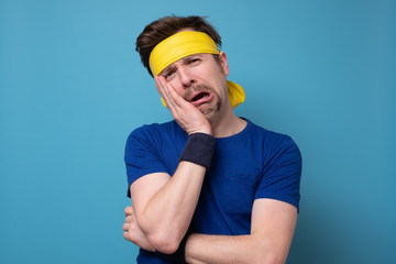 Young caucasian sport man frowning face in displeasure, keeps arms folded.