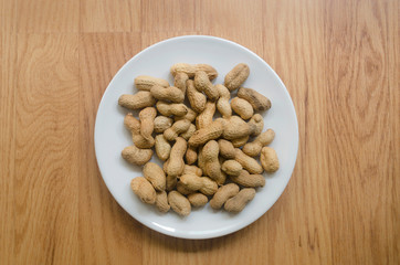 Platel of peanuts in their shells, flay lay.