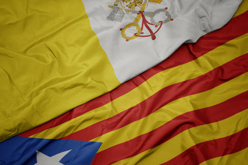 waving colorful flag of catalonia and national flag of vatican city.