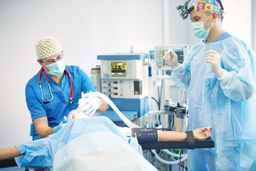 Several doctors surrounding patient on operation table during their work. Team surgeons at work in...