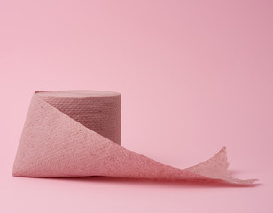 untwisted roll of pink toilet paper on a pink background