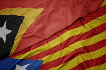 waving colorful flag of catalonia and national flag of east timor.