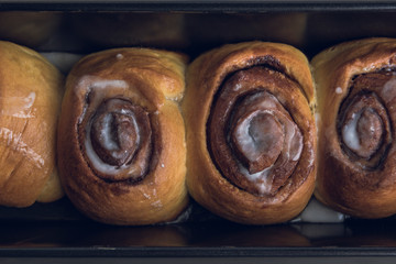 Close-up of a black baking pan with fresh homemade cinnamon rolls.