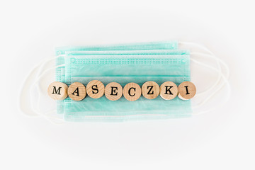 Words written with wooden blocks with black letters laying on protective surgical masks 