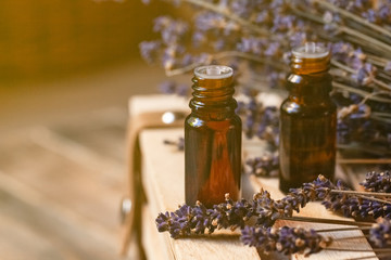 Organic natural essential lavender oil in small brown glass bottles. Dry flowers, wooden background. Concept of natural cosmetics. Faded colors, tonned in yellow. Close up, macro, copy space