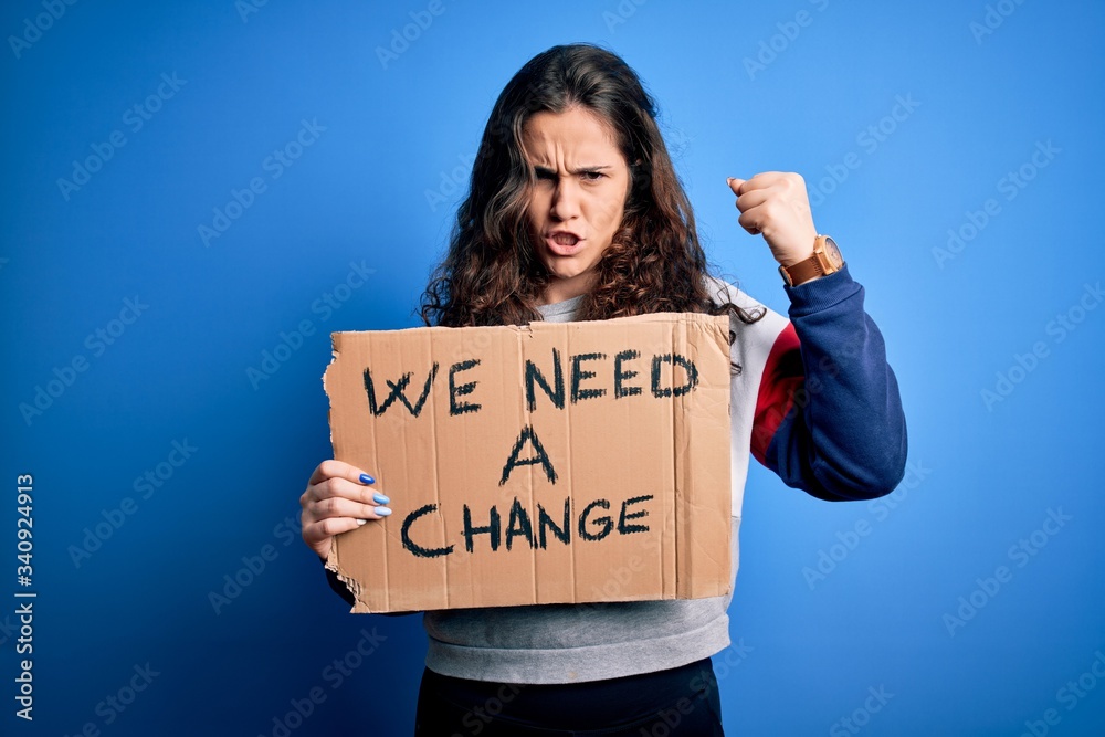 Sticker young beautiful activist woman holding banner with change message over blue background annoyed and f