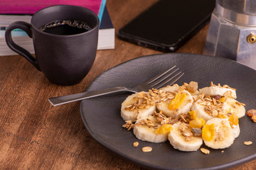 plate with sliced banana, granola, candied fruit and honey, toast and a cup of coffee