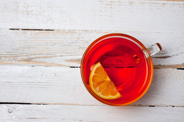 Glass cup with tea and lemon standing on a white painted wooden surface. Background for hot drinks....