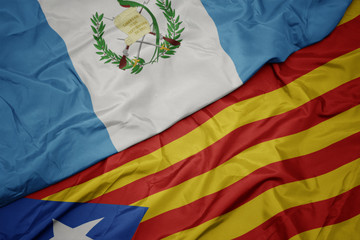 waving colorful flag of catalonia and national flag of guatemala.