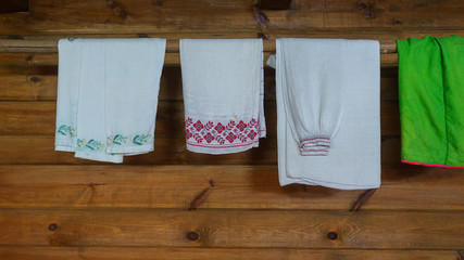 Traditional slavic clothes and linen with ornaments are dried in a wooden house. Space for text.