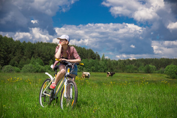 Obraz premium a young woman with a Bicycle in a summer meadow on a Sunny day