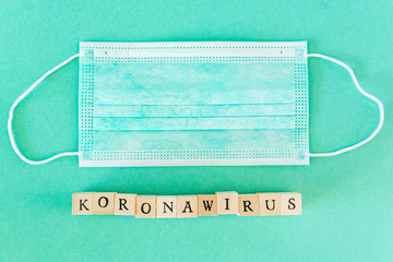Word written with wooden blocks with black letters laying on protective surgical masks....