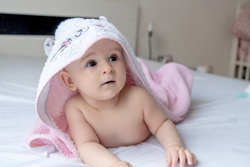 Six month baby girl wearing towel after bath. Childhood and baby care concept