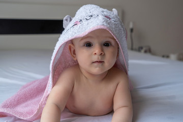 Six month baby girl wearing towel after bath. Childhood and baby care concept