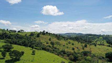 Fototapeta na wymiar Brazilian farm with pastureland among mountains and native Cerrado vegetation. Ceres, Goias State, Brazil 