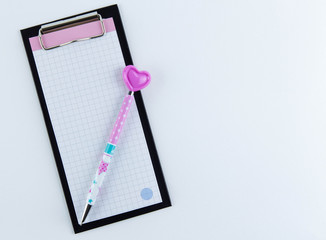 Notepad and pink pen with a heart. Space for romantic wishes text, sign. Valentine's Day, March 8th.