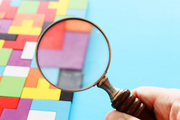 concept image of magnifying glass over puzzle background. finding the right piece.