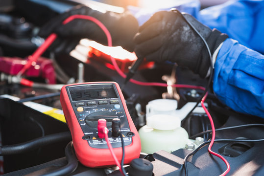 The abstract image of the technician using voltage meter for voltage measurement a car's battery. the concept of automotive, repairing, mechanical, vehicle and technology.