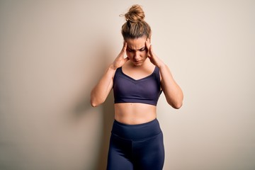 Young beautiful blonde sportswoman doing sport wearing sportswear over white background with hand on head for pain in head because stress. Suffering migraine.