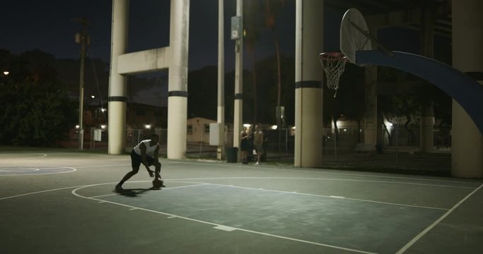 Man playing basketball at night
