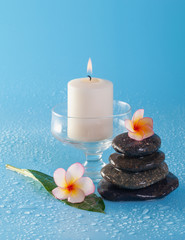 Spa stone pile with flowers and water drops on a blue background