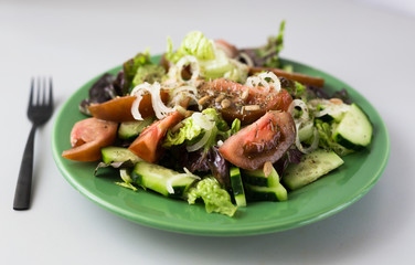 vegetable salad of greens, tomatoes and cucumbers on a green plate