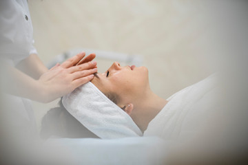 young woman during cosmetological procedure of face massage