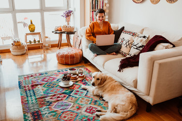 .Young freelance woman working from home with her laptop accompanied by her faithful golden retriever during the quarantine. Stay home. Lifestyle
