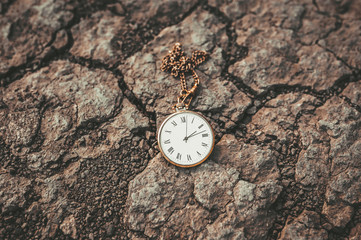 Old pocket watch on dry ground. Change of times and eras.