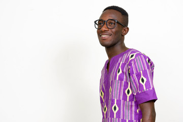 Profile view of happy young African man in traditional clothing thinking