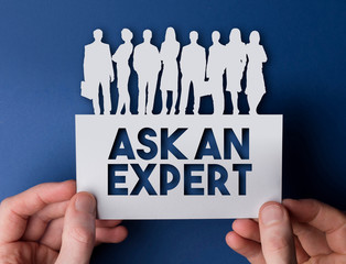 Hands holding an ask an expert white card business team people sign