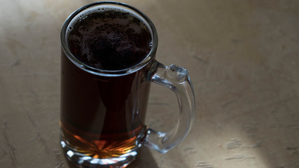 Glass mug of dark beer on the table with copy space
