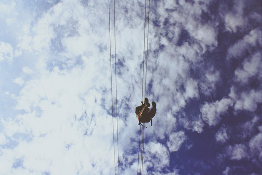 Directly Below View Of A Person Using Aerial Lift Against Cloudy Sky