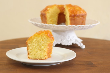 Slice of homemade orange cake with orange icing. White background.