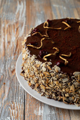 Close up of chocolate and cherry cake with almond flakes and golden chocolate decoration