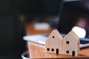 Wooden house model on workplace table background in work from home concept.