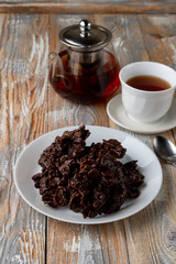 No-bake corn flakes cookies with dry fruits, nuts and raisins with a cup of black tea on old wooden table