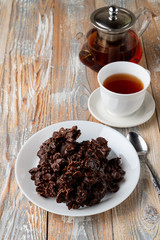 No-bake corn flakes cookies with dry fruits, nuts and raisins with a cup of black tea on old wooden table