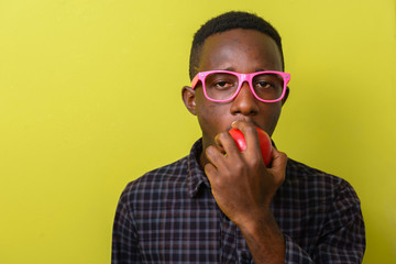 Face of young African hipster man eating apple
