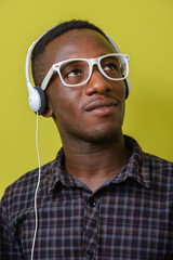 Face of young African hipster man with eyeglasses listening to music