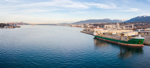 Naklejka na ściany i meble Aerial drone shot of a industrial shipyard and cargo ship loading port with cargo ships in Vancouver, BC, Canada.