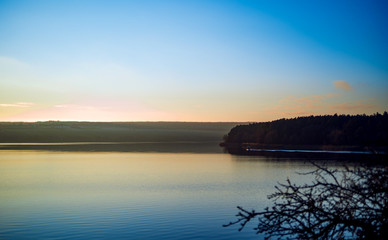 Peaceful rural landscape. Beautiful river with blue sky above at sunrise.