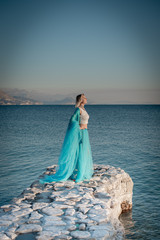 Young woman on the sea in blue dress