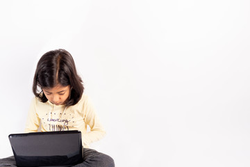 Cute little girl is using her notebook and headphones