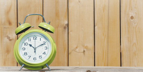Retro alarm clock on wooden rustic background.