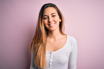 Obraz premium Young beautiful blonde woman with blue eyes wearing white t-shirt over pink background with a happy and cool smile on face. Lucky person.