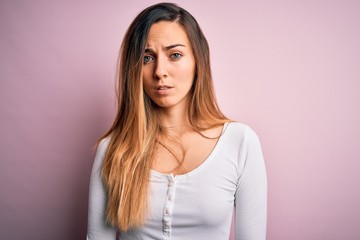 Young beautiful blonde woman with blue eyes wearing white t-shirt over pink background skeptic and nervous, frowning upset because of problem. Negative person.