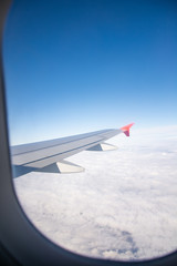 Fototapeta premium Airplane wing and clouds are visible from the porthole.