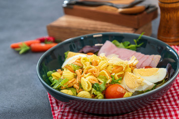 Salad made with cooked pasta, mixed green salads, cherry tomatoes, Mozzarella cheese and smoked ham served with accompaniment