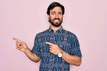 Young handsome hispanic bohemian man wearing hippie style over pink background Pointing aside...